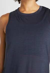 Top sportivo senza maniche di un blu scuro navy, realizzato in un tessuto leggero e liscio con scollatura rotonda e vestibilità comoda. Presenta una texture sottile in tutta la superficie.