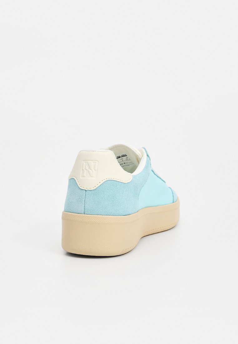 Zapatilla deportiva de ante azul claro con un acento en el talón color crema, punta redondeada y suela gruesa beige. Cuenta con un emblema de logo en el talón.