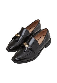 Mocassins en cuir noir avec une finition brillante, présentant un accent de lanière avec des matériaux en or et un détail de pampilles. Semelle plate et design à bout rond.
