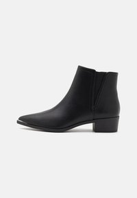 Black leather ankle boot with pointed toe, low stacked heel, elastic side panel, and smooth texture on a white background.