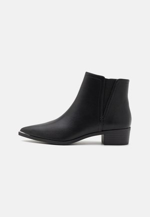 Black leather ankle boot with pointed toe, low stacked heel, elastic side panel, and smooth texture on a white background.