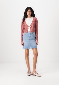 Rød og hvit rutete kort cardigan med knyting i front, sammen med et lys blått denim-skjørt. Brukt med myke rosa loafers.