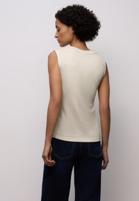Svetle béžový tílko bez rukávů z texturovaného, lesklého materiálu. Design zahrnuje kulatý výstřih a přiléhavý střih.