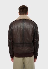 Chaqueta bomber de cuero marrón con un cuello de forro polar, dobladillo y puños de canalé, con costuras visibles y una textura suave.
