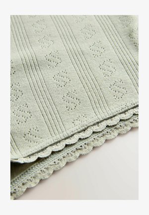 Svetlo zelena teksturirana tkanina z dvignjenimi vzorci, ki vsebuje pletene črte in valoviti čipkast rob. Mehka, gladka površinska obdelava.