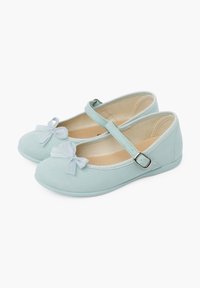 Scarpe Mary Jane in tela azzurra chiara con punta rotonda, suola piatta e un fiocco decorativo sul davanti. Presentano una fascia con chiusura a fibbia.