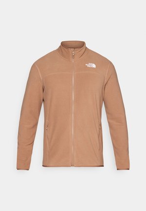 Braune Fleecejacke mit hohem Kragen, Reißverschlussschluss und zwei Seitentaschen. Verfügt über ein kleines weißes Logo auf der obersten linken Seite. Glatte Textur.