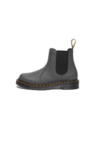 Botín de cuero gris hasta el tobillo con lados elásticos, costuras amarillas y una lengüeta. Presenta un upper texturizado y una suela de goma resistente.