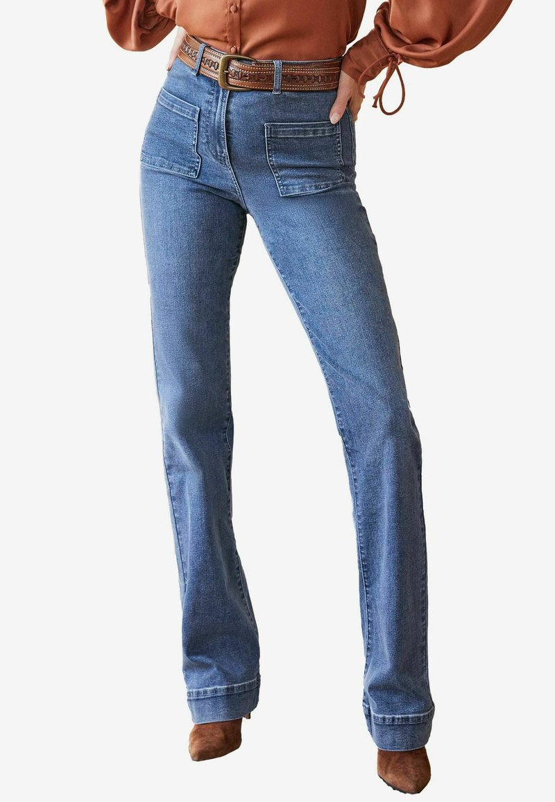 Jeans a zampa d'elefante in denim azzurro chiaro con due tasche frontali, vita alta e una cintura intrecciata marrone. Tessuto liscio e colore uniforme in tutto.