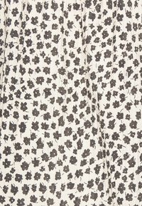 Tessuto bianco con motivi floreali neri sparsi, caratterizzato da una superficie texture e leggermente stropicciata. Il design include piccoli fiori e foglie.