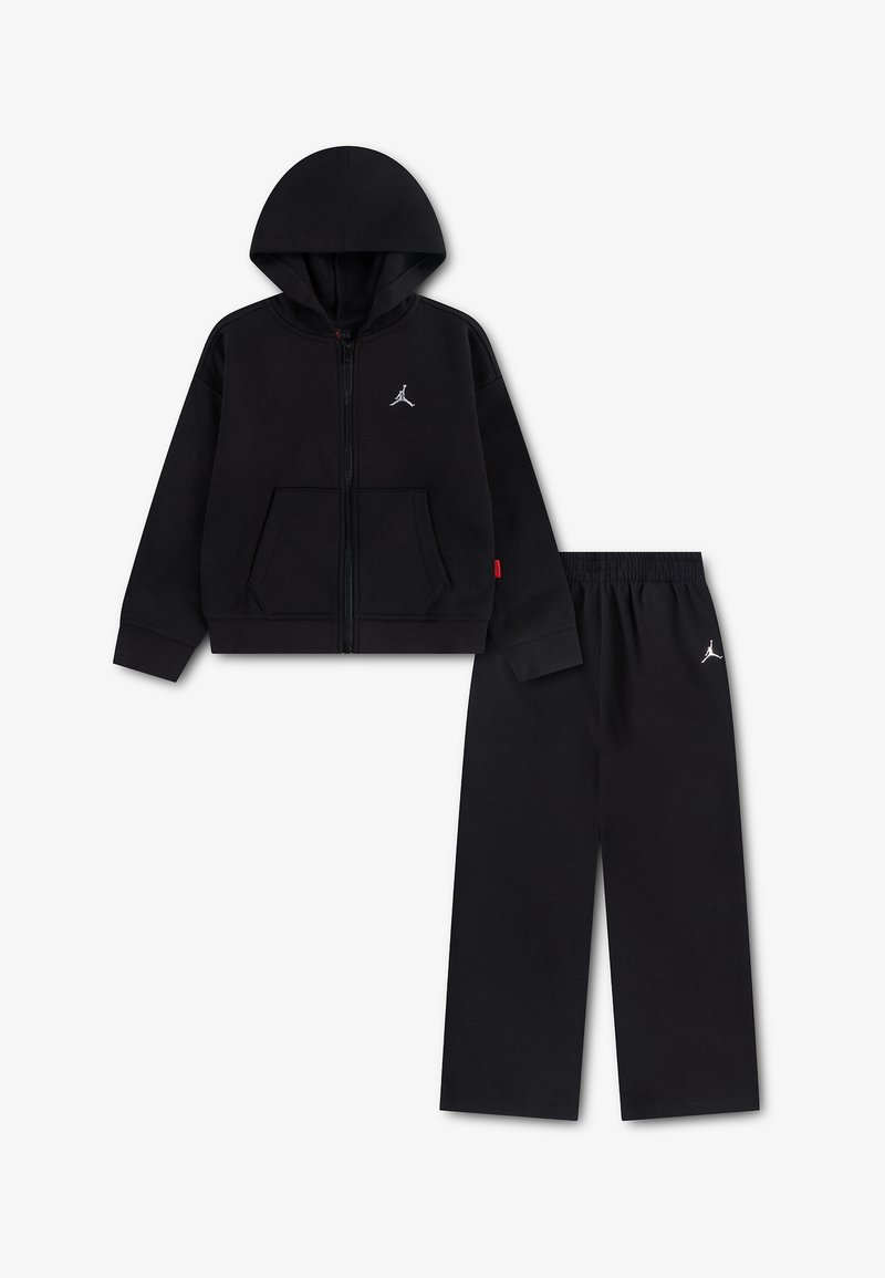 Sweat à capuche zippé noir et pantalon noir assorti avec logos Jumpman blancs, présentés à plat sur fond blanc.