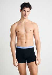 Melnas boksa bikses no kokvilnas ar gaiši zilu jostu, uz kuras redzams "BJÖRN BORG" logo. Gluda tekstūra, pieguļošs dizains.