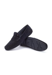 Los mocasines de ante negro cuentan con un upper texturizado, una solapa delantera cosida y una suela de goma flexible con un dibujo para mayor tracción.