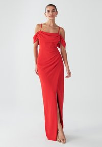 Rotes langes Kleid mit schulterfreien Ärmeln, geraffter Textur, tailliertem Oberteil und seitlichem Schlitz. Glatter Stoff mit schlankem Design.