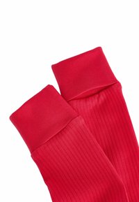 Červené rebrované podkolienky s hladkým povrchom a širokými manžetami. Materiál je elastický, čo zabezpečuje tesné usadenie. Bez ďalších vzorov či akcentov.