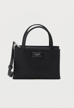 Bolso negro de Kate Spade New York con dos asas y una correa de hombro ajustable sobre un fondo liso.