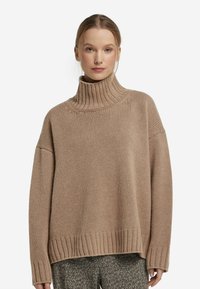 Jasnobrązowy, oversize sweter z golfem, z prążkowanym dekoltem i hemem. Teksturowana dzianina, luźny krój, z obniżonymi ramionami.