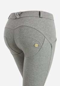 Leggings grigi realizzati in tessuto morbido, con una vita alta, cuciture curve e un piccolo accento metallico con il marchio vicino alla tasca posteriore.