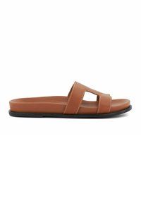 Tan leren slip-on sandalen met twee uitsparingen, platte zwarte zool en witte stiksels langs de randen voor extra contrast.