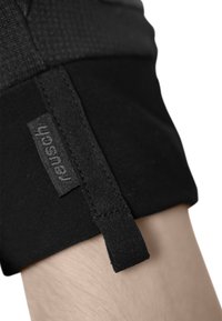 Schwarzer elastischer Stoff mit einem strukturierten oberen Abschnitt, der ein eingenähtes Etikett und eine kleine Stoffschlaufe aufweist. Das Design ist minimalistisch und funktional.