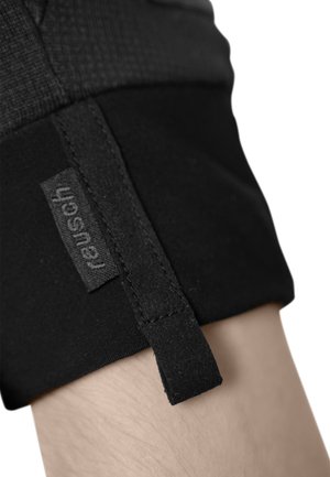 Tessuto elastico nero con una sezione superiore testurizzata, dotato di un'etichetta cucita e di un piccolo anello di tessuto. Il design è minimalista e funzionale.