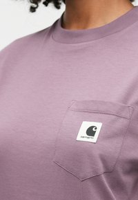 Λεβάντα βαμβακερό t-shirt με στρογγυλή λαιμόκοψη, διαθέτει τσέπη στο στήθος και ετικέτα με λογότυπο. Λείος υφασμάτινος χαρακτήρας και κανονική εφαρμογή.