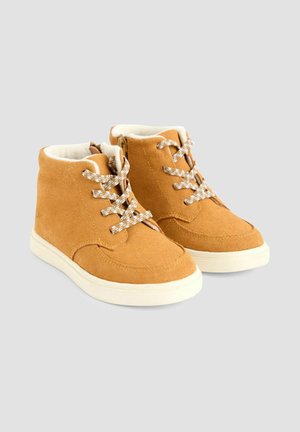 Ruskokottiset nilkkasaappaat, joissa on pehmustettu valkoinen vuori,BEIGE nauhat ja vetoketjusulku sivussa. Ominaisuuksiin kuuluu pyöreä varvas ja kumipohja.