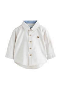 Lysebeige skjorte med knapper foran og lange ærmer, med en denimkrave og en lille bjørn broderet på brystet. Træknapper og afrundet nederkant.