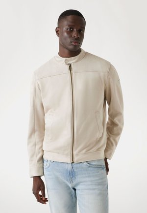 Light beige suede jacket with a high collar, zip front, and side pockets. Features a smooth texture and subtle stitching details.