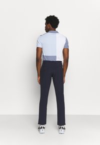 Polo shirt with blue and white color blocks, short sleeves, and a collar, paired with navy trousers and white sneakers. Smooth texture.