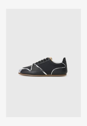 Black athletic shoe with a smooth leather upper, metallic silver accents, and rounded toe. Features a textured, slip-resistant sole.