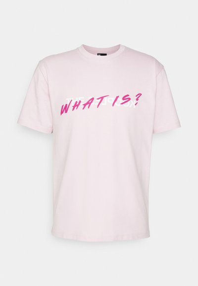 Lys rosa bomulls t-skjorte med korte ermer, med fet hvit og rosa tekst som står "HVA ER?" på forsiden. Klassisk crew neck-design.
