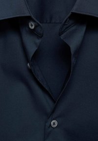 Navyblauwe shirt met een button-down kraag, twee knopen bij de nek en een gladde stofstructuur. Geen zichtbare patronen of accenten.