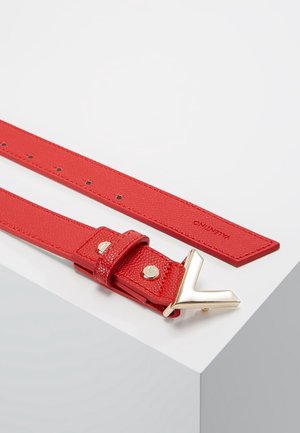 Roter Ledergürtel mit goldener V-förmiger Schnalle und in der Nähe der Spitze geprägtem Valentino-Logo, flach auf einer weißen Oberfläche liegend.