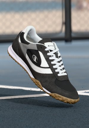 Black and gray athletic shoe with suede and synthetic materials, white accents, laces, and a textured rubber sole for traction.