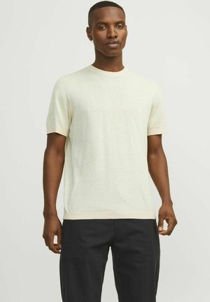 Pull court à manches courtes beige clair en maille douce et texturée. Présente un col rond et un contraste léger au niveau des manches et de l'ourlet.
