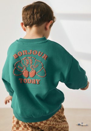 Teal Sweatshirt mit Rundhalsausschnitt, ausgestattet mit einem erhabenen orangen Grafikmotiv von Cartoon-Croissants und dem Text „BONJOUR TODAY“ auf der Rückseite.