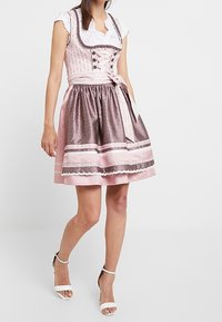Tradycyjna sukienka dirndl z dopasowanym gorsetem w różowo-białym wzorze kwiatowym, rozszerzającą się satynową spódnicą i koronkowymi akcentami.