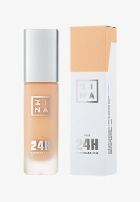 Botella de base transparente y esmerilada con líquido beige y tapa plateada. Acompañada de una caja de embalaje blanca con acentos naranjas.