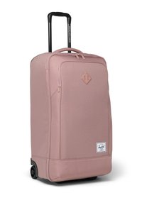 Růžový kufr na kolečkách s texturovanou tkaninou, detailem v podobě diamantového vzoru, horní rukojetí a sklopnou černou rukojetí. Obsahuje dvě černá kolečka.