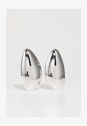 Dva srebrna metalna ukrasna komada, u obliku suze, s glatkom, reflektirajućom površinom i kontrastnom mat podlogom.