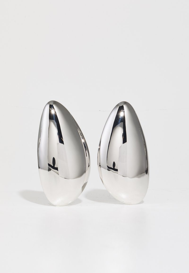 Deldi dva srebrna kovinska dekorativna kosa v obliki kapljice, z gladko, odbojno površino in kontrastno mat podlago.