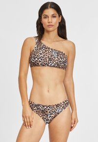 Ensemble de bikini imprimé léopard avec un haut à une épaule et un bas hipster assorti. Le matériau présente une texture lisse et extensible.