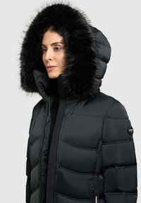 Sort puffjakke med høj krave, der har en stor faux fur hætte. Glat tekstur, lynlåslommer og et logo på ærmet.