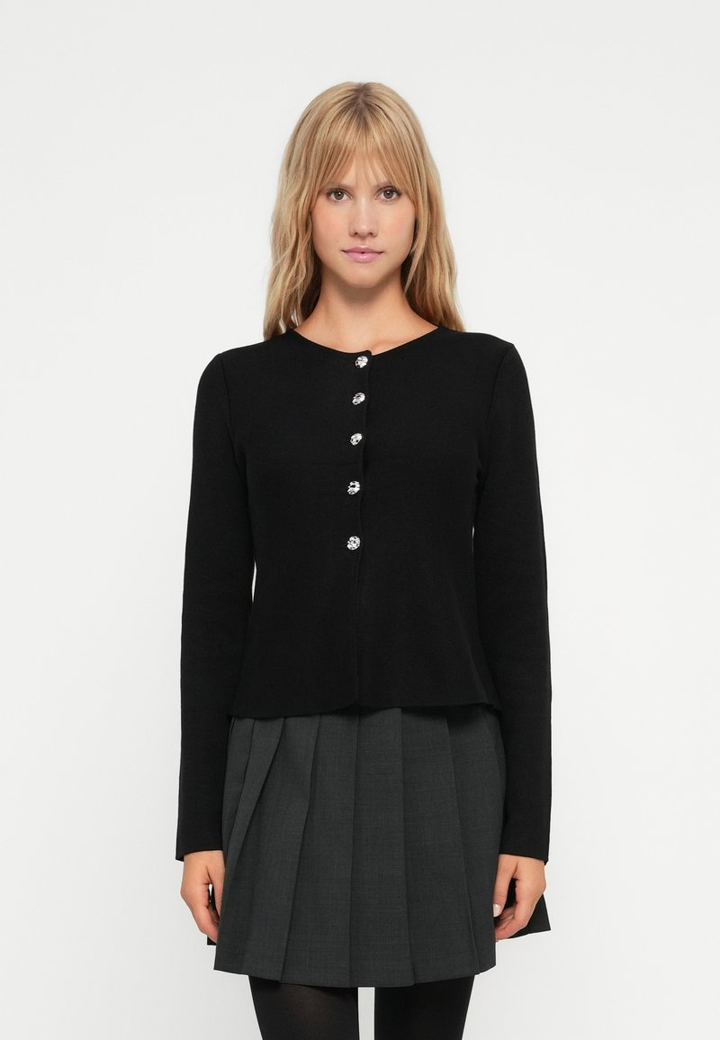 Cardigan noir à manches longues avec un col rond et cinq boutons en argent. Tissu tricoté ; coupe droite.