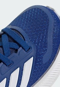 Navy blue athletic shoe with mesh upper, textured detailing, and white accents; features padded tongue and lace-up closure.