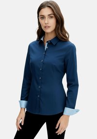 Navy blue button-up shirt with long sleeves, featuring a light blue striped cuff and collar. Smooth texture and tailored fit.