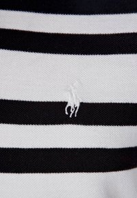 Tissu à rayures horizontales noires et blanches avec un petit logo brodé blanc représentant un cheval et un cavalier au centre.