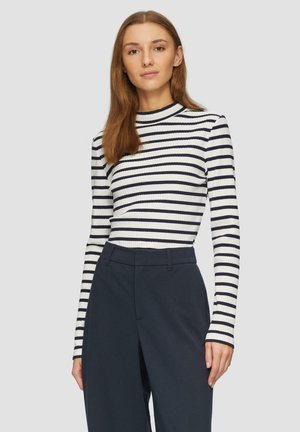 Ribbed long-sleeve top featuring navy and white vertical stripes, high neckline, and a fitted silhouette, paired with high-waisted dark trousers.