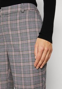 Šedé kárované kalhoty s černým, růžovým a béžovým vzorem kostek; střih na míru s hladkou texturou a bočními kapsami.